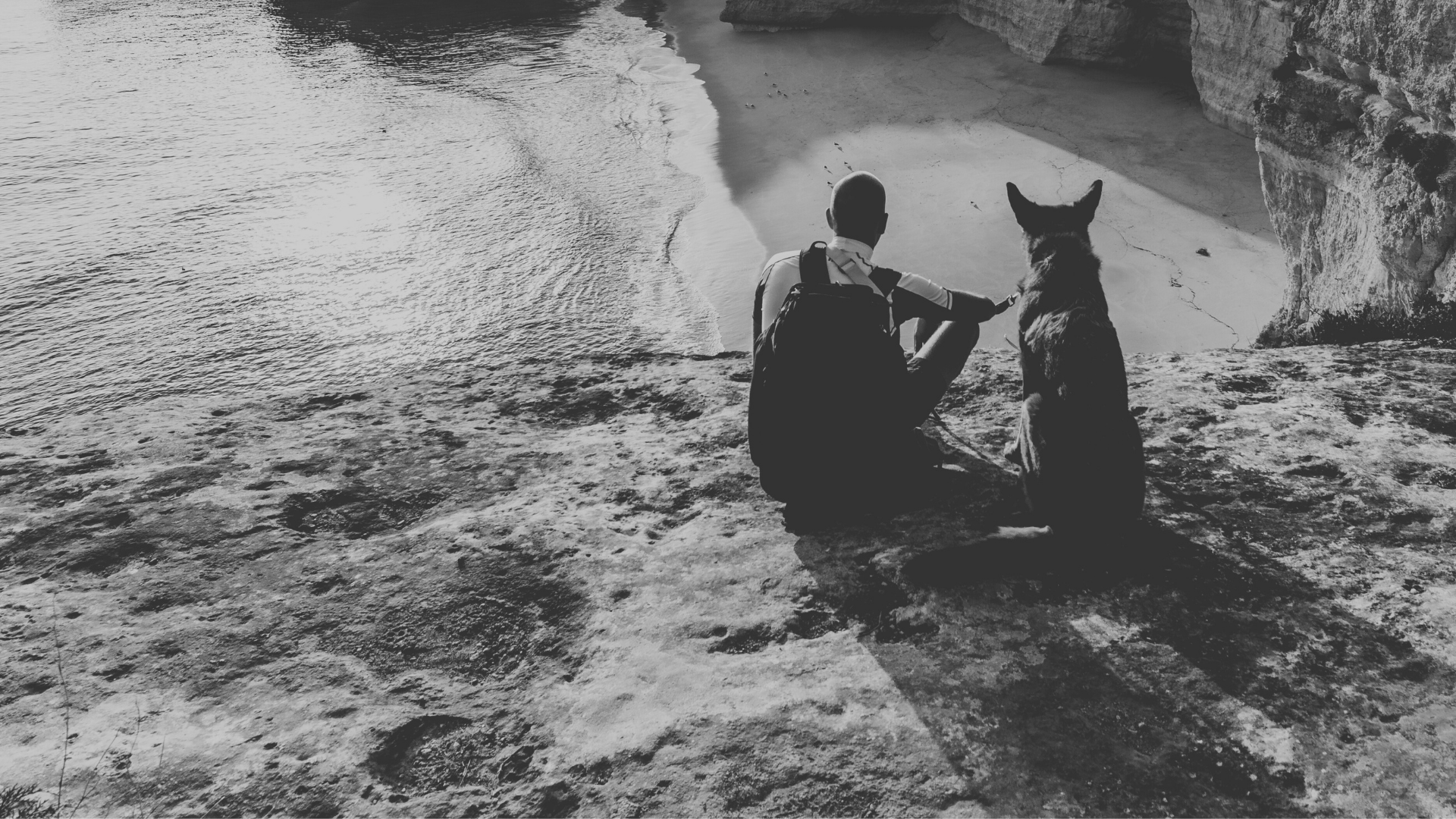Black and white photo of a man with his dog standing on a cliff, symbolizing Genesee BioMedical’s mission of dedication and trust